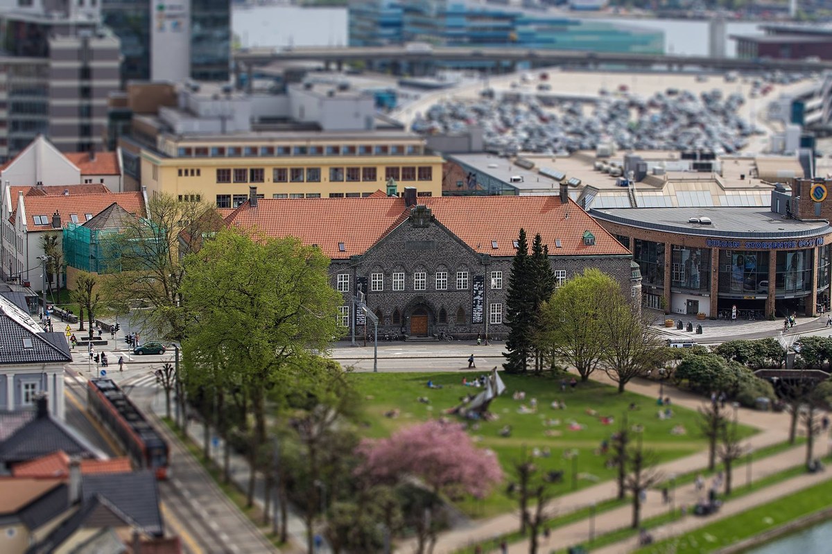 Aerial view of Bergen Public Library, a large stone building with a red tiled roof. The building has a symmetrical façade with many windows and a prominent main entrance in the center.