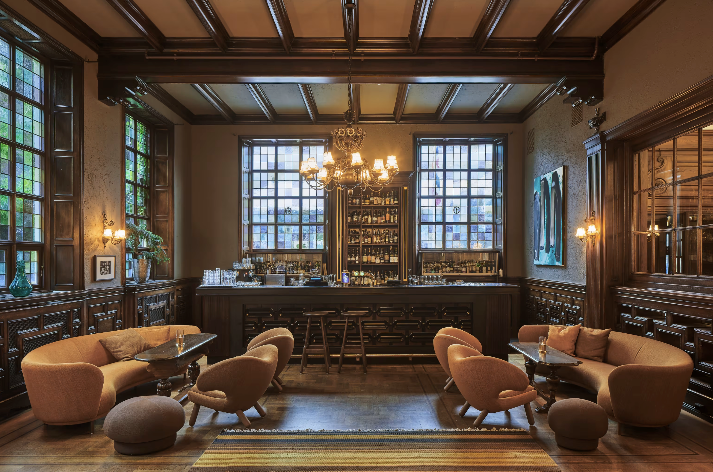 Elegant hotel lobby with dark wood paneling, chandeliers, and a check-in desk.